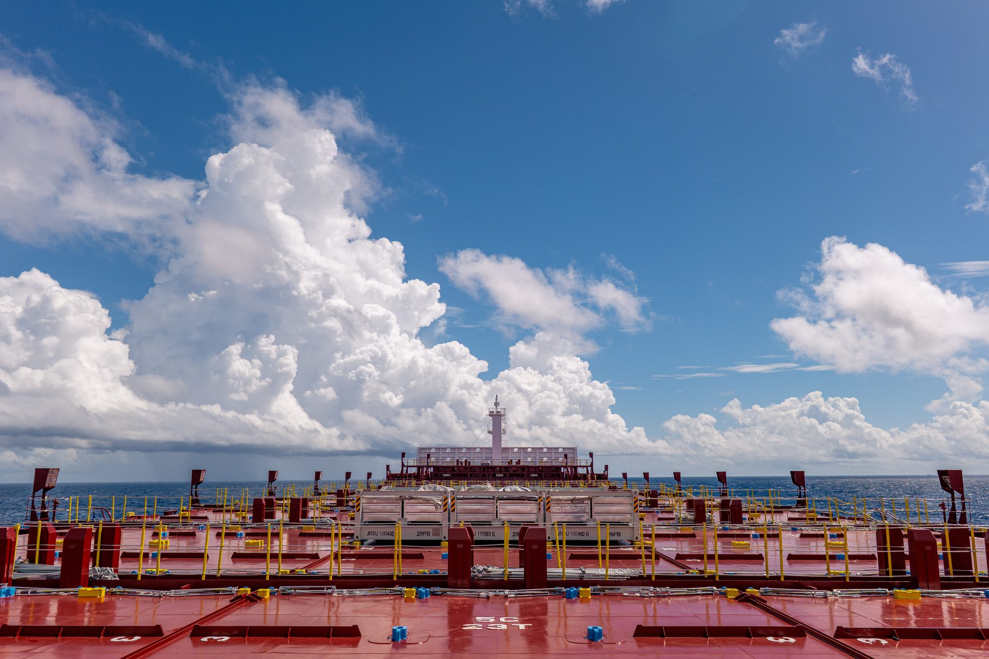 Container ship deck beneath cumulus clouds, Taiwan Strait