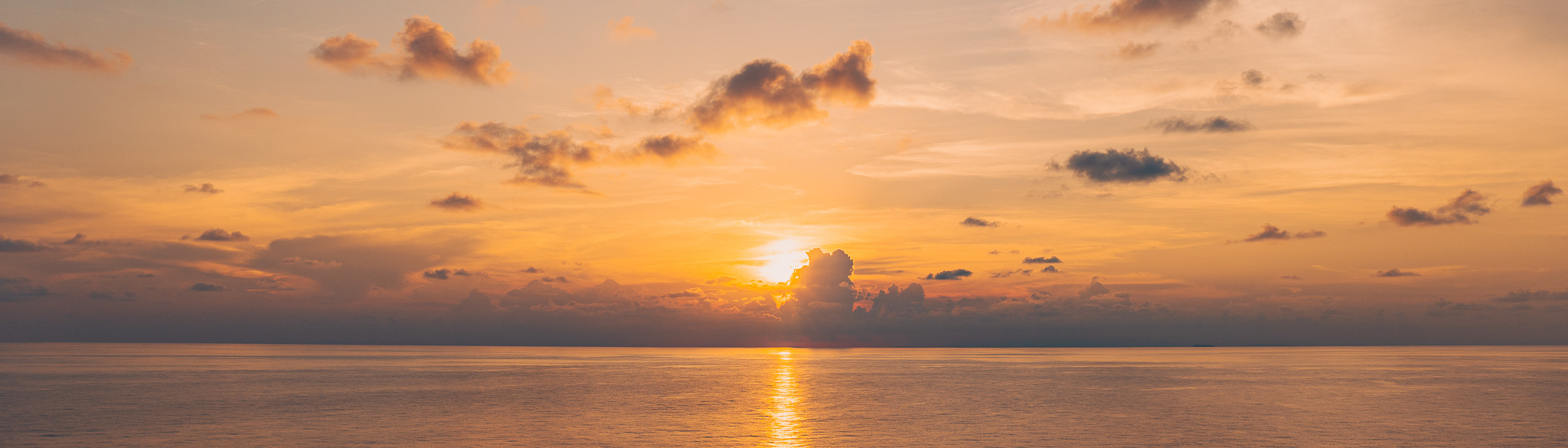 Panoramic view of the sun setting over open water